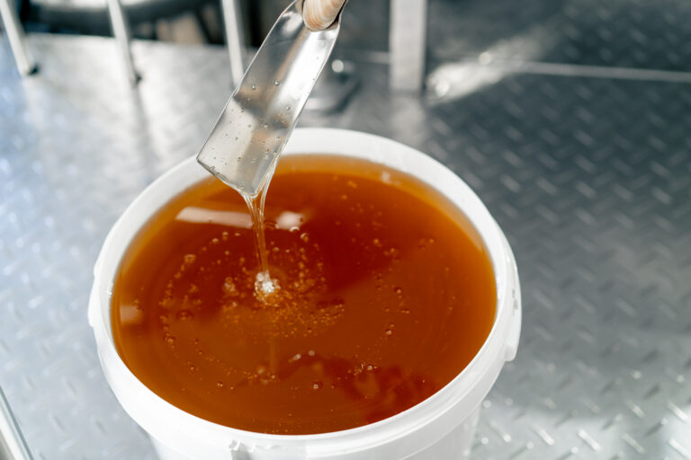 Top shot of a special metal spoon mixing a fluid oil which flows back into a large bowl